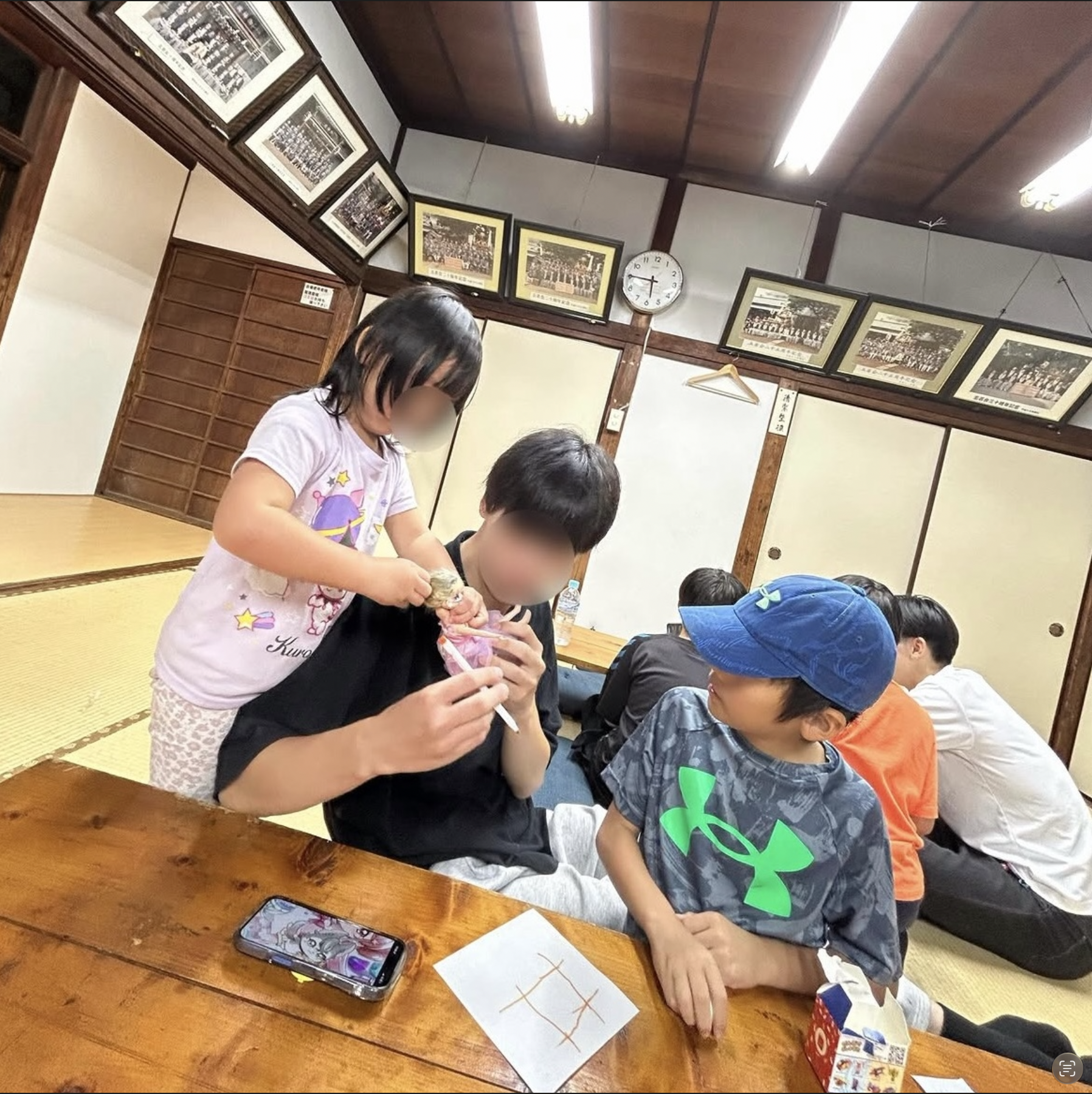 集会所のテーブルを囲んで、子どもたちとスタッフがおもちゃで遊ぶようす